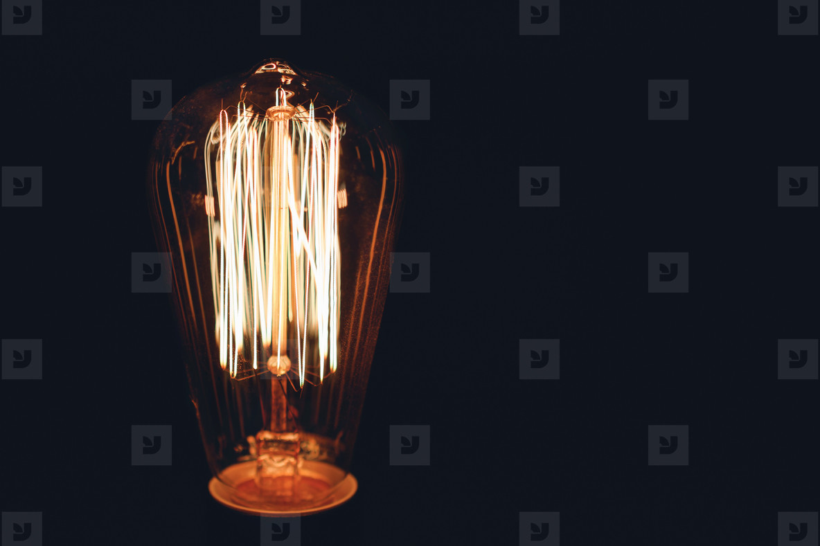Close up of glowing retro light bulb on a black background  Copy space