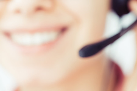 Smiling girl in the headset is working in the customer support center  Blurred image