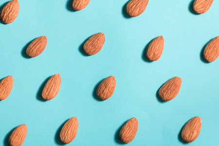 Symmetrical pattern of almonds on blue  Flat lay