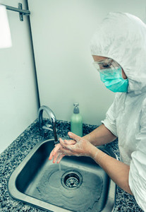 Woman in bacteriological protection suit washing hands