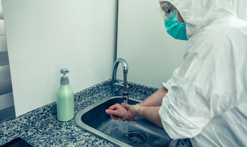 Woman in bacteriological protection suit washing hands