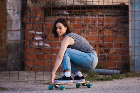 Young skater woman riding on her longboard in the village