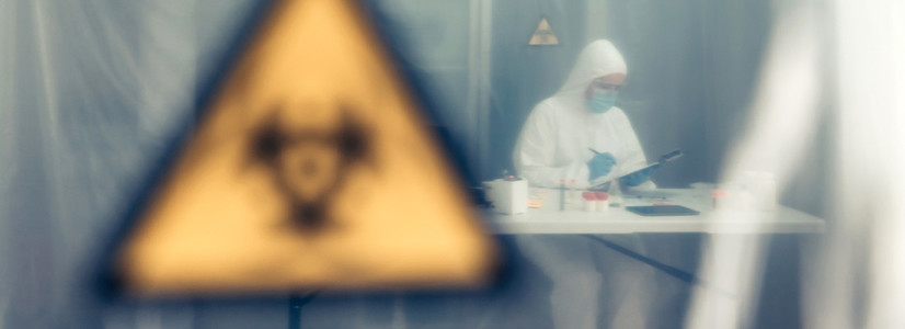 Scientist investigating in the laboratory behind a protective cu