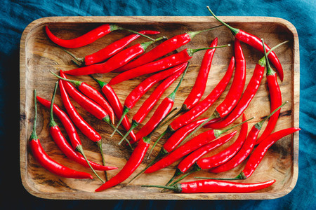 A lot of chili peppers on a wooden tray  Top view