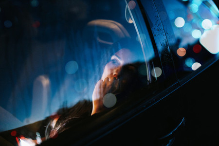 Young woman inside a car looking away through the window