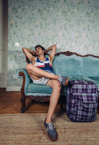 Man with suitcase waiting sitting on a sofa