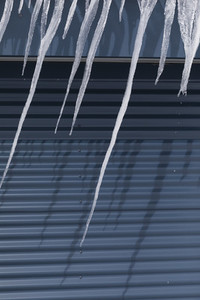 Sharp icicles melting over blue garage door