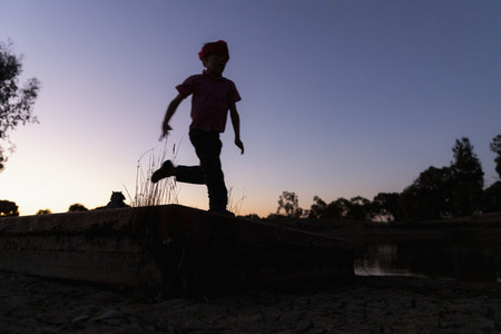 Silhouette boy running against twilight sky