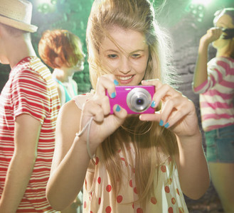 Playful teenage girl using digital camera at party