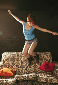 Carefree teenage girl jumping on sofa
