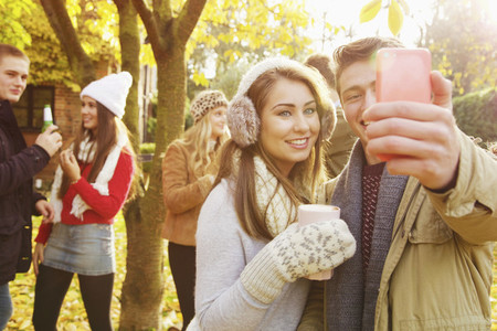 Happy teenage couple taking selfie with smart phone