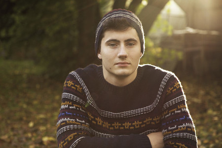 Portrait confident teenage boy in sweater and knit hat