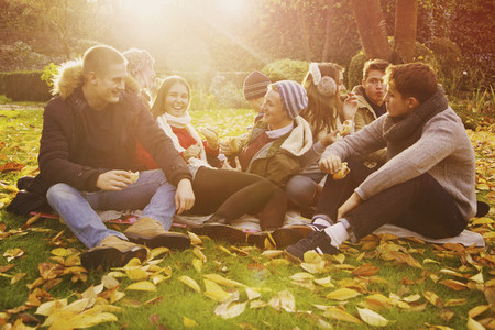 Friends hanging out and enjoying picnic in sunny autumn park