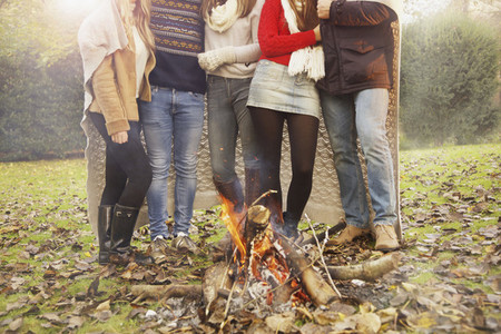 Teenage friends enjoying campfire in autumn park