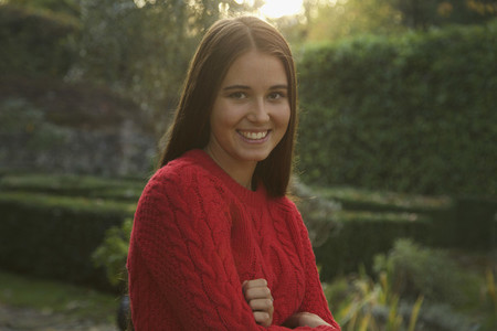 Portrait smiling teenage girl in red sweater in autumn park