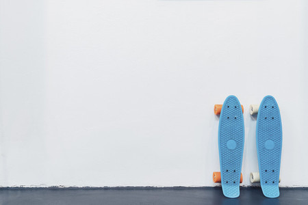 Blue skateboards leaning against white wall