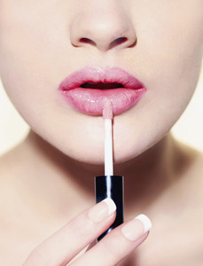 Close up woman applying lip gloss
