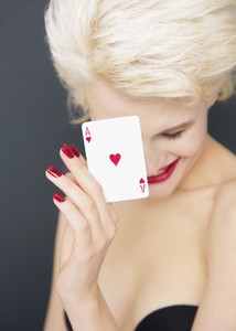 Portrait young blonde woman holding red Ace of Hearts card