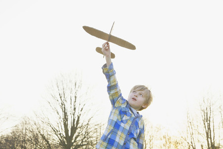 Boy playing with cardboard airplane in park