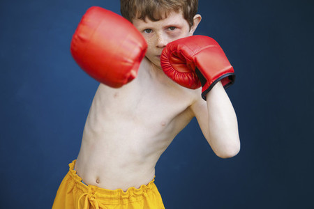 Portrait tough boy with black eye wearing boxing gloves in fighting stance