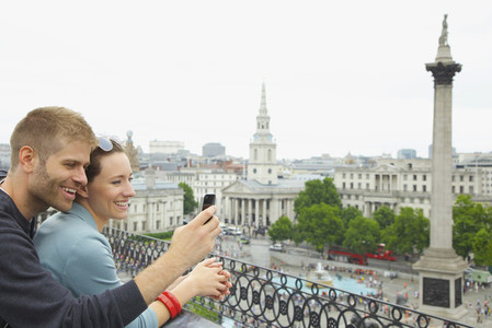 Happy couple using camera phone above Trafalgar Square