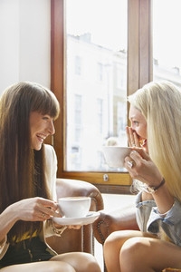 Happy young women drinking coffee in cafe window