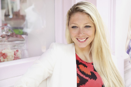 Portrait smiling young blonde woman outside bakery