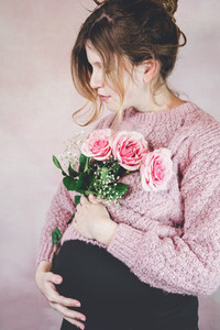 Young pregnant woman holding a bouquet of roses