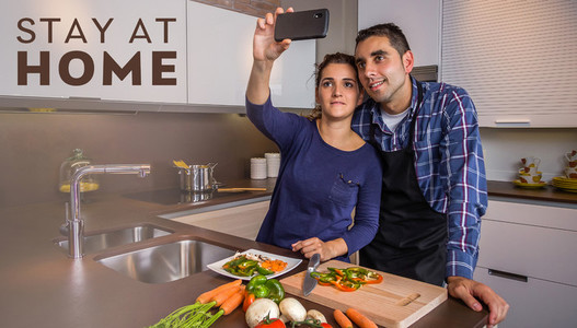 Couple in kitchen cooking and taking selfie with smartphone
