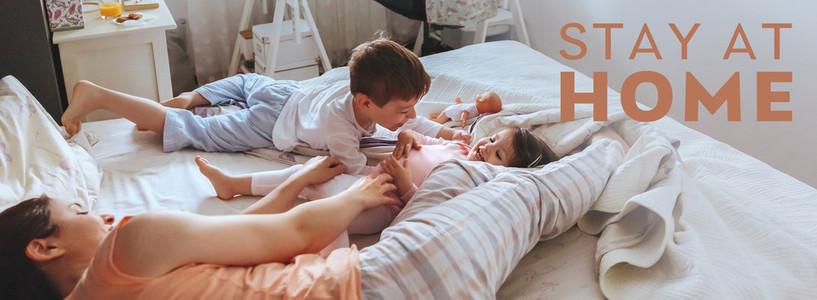 Relaxed mother and sons playing over the bed