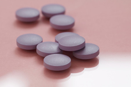 Close up of purple pills on a pink background