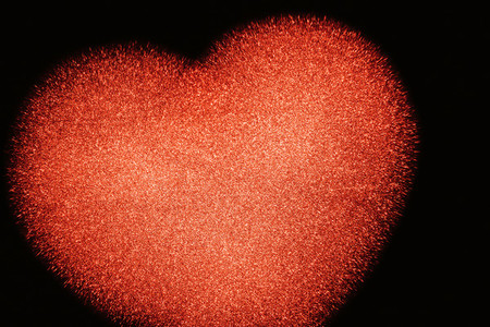 The background of a cropped red shiny heart on black