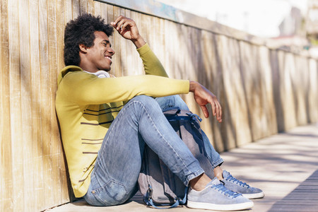 Black man with afro hair and headphones resting on the ground