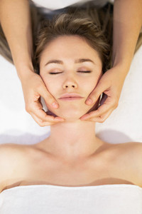 Young blond woman receiving a head massage in a spa center