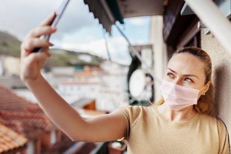 Woman taking a selfie during quarantine in her balcony