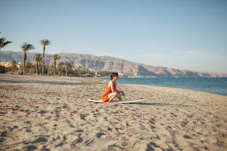 Young woman in the beach with her surf table waiting in the sand