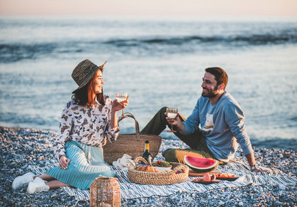 Young couple having picnic at seaside with wine