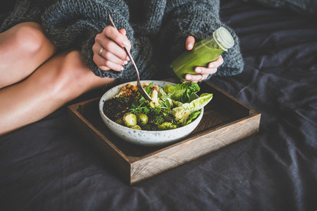 Healthy vegan bowl on tray and woman eating
