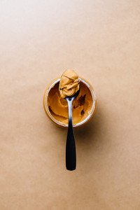 Opened peanut butter with black spoon  Shelf vegetarian food concept  Minimal style photography