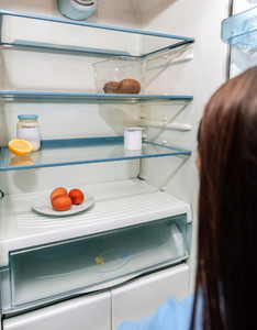 Girl looking at empty fridge due to a crisis
