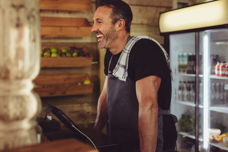 Smiling cafe worker standing at checkout counter