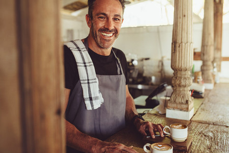 Happy male barista in a coffee shop