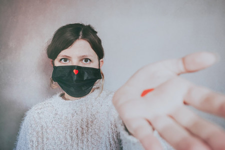 Young woman wearing a mask with a red heart on it