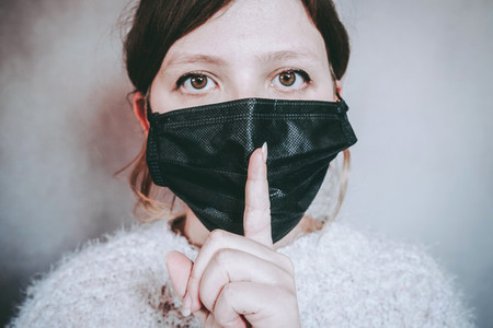 Young woman wearing a face mask and asking for silence
