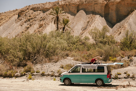 Woman practicing yoga on the roof of a van in the desert