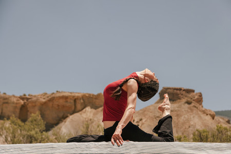 Woman practicing yoga on the roof of a van in the desert