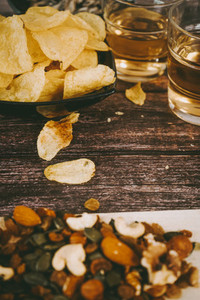 Mix of snacks with chips  nuts  seeds and beer