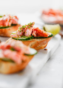 Toasts with fresh cucumber and smoked salmon served with lime shavings
