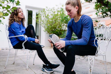 Two young sportswomen tying her shoelaces before the training