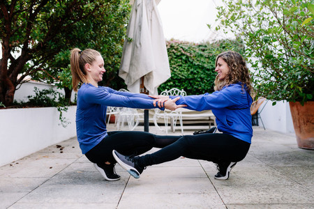 Two young women doing exercise together on a terrace